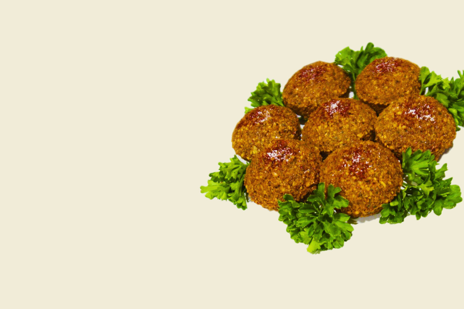 Plate of crispy falafel balls with garnish on a beige background.