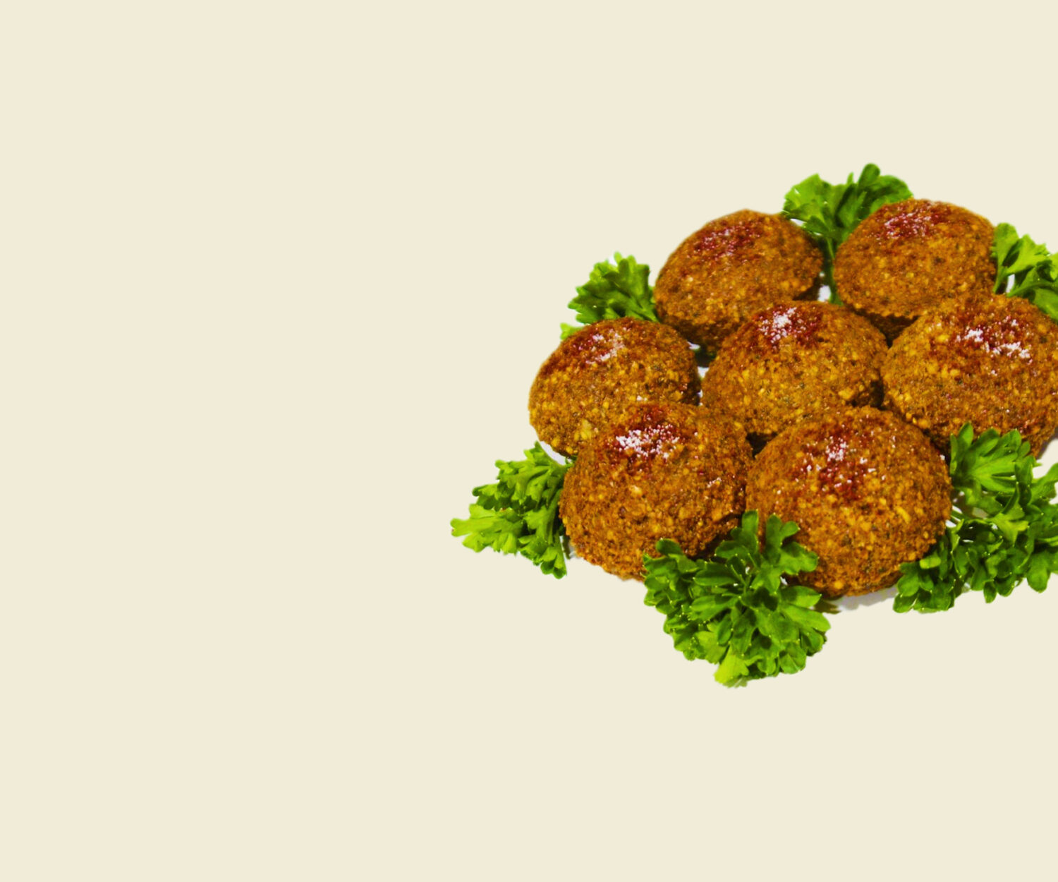 Plate of crispy falafel balls with garnish on a beige background.