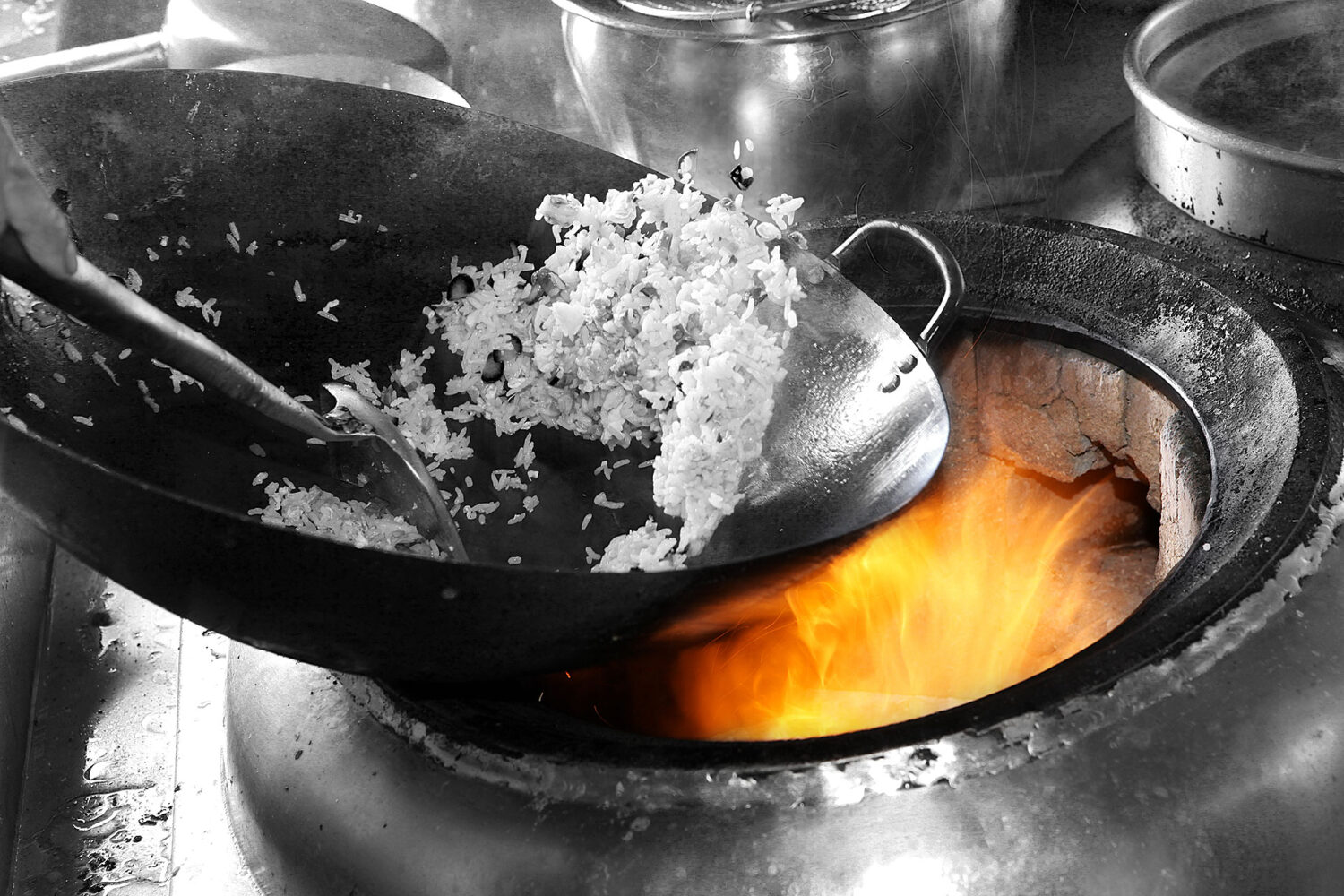 Rice being poured into a pot over a flame.