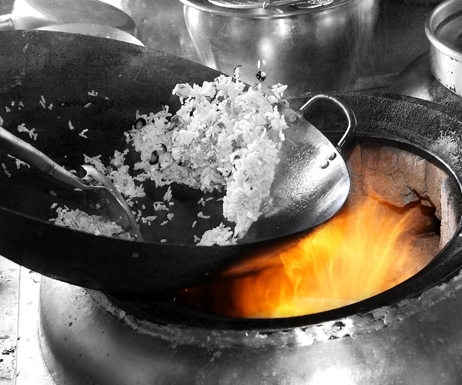 Rice being poured into a pot over a flame.