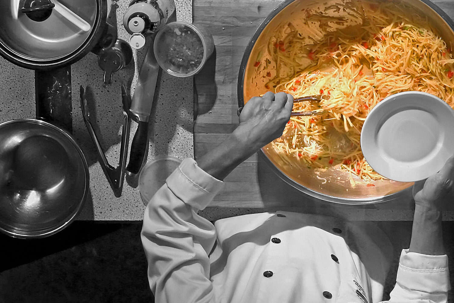 Chef seasoning a large pot of soup in a kitchen.