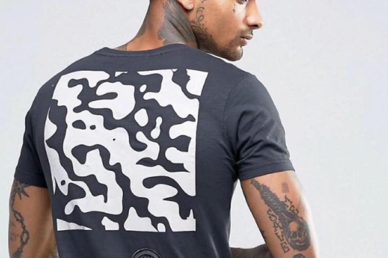 Man wearing a black t-shirt with a bold white abstract pattern on the back.
