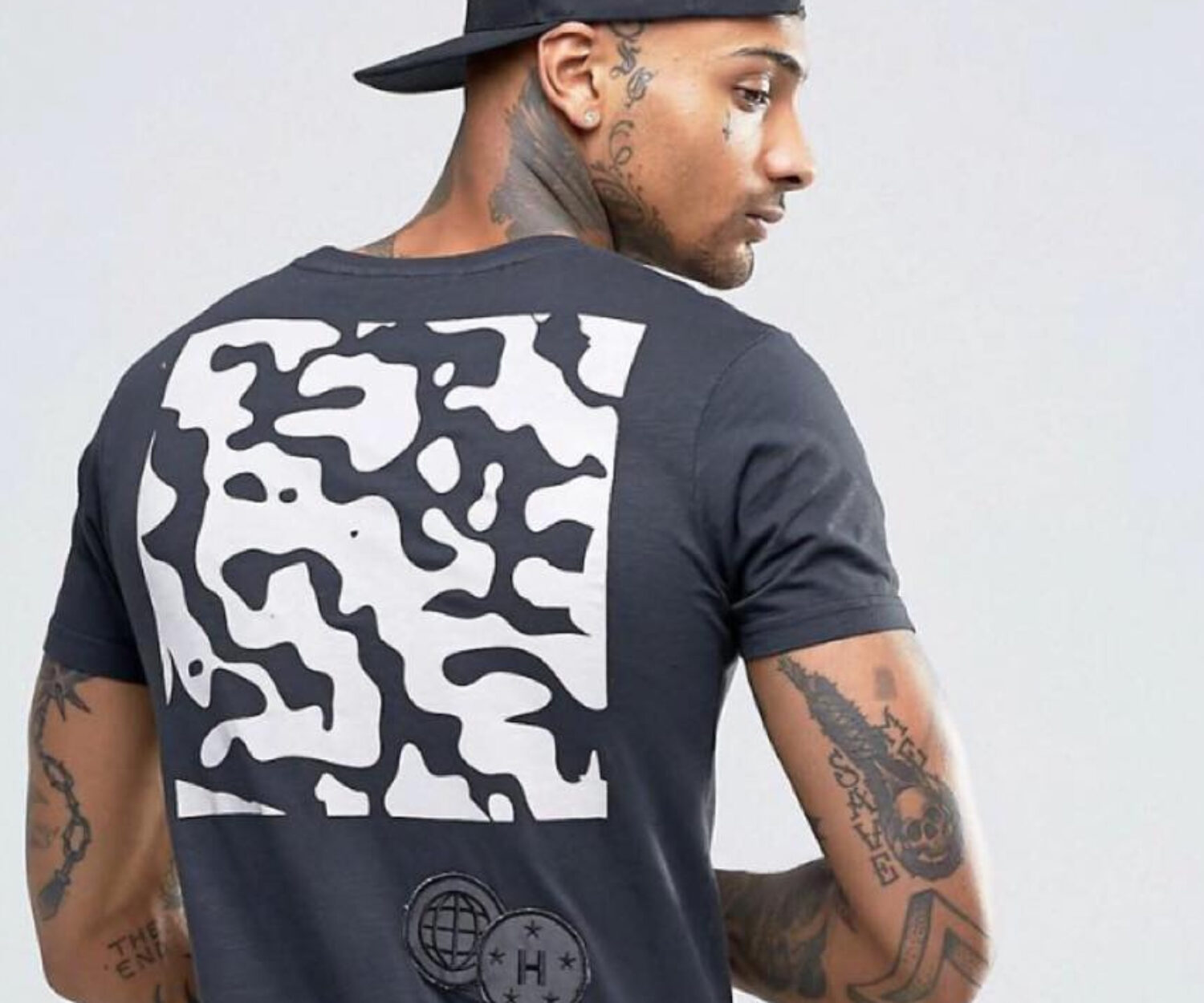 Man wearing a black t-shirt with a bold white abstract pattern on the back.